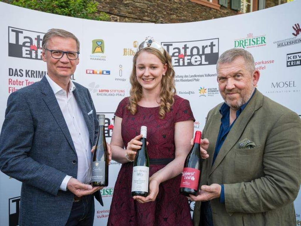 Günther Jauch (l), Mosel-Weinkönigin Laura Gerhardt und Dietmar Bär präsentieren die drei Festivalweine für das Krimifestival "Tatort Eifel". Foto: Oliver Dietze