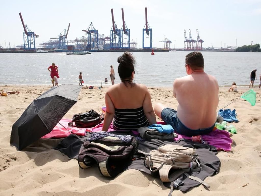 Am Elbstrand in Hamburg: Ausflügler sitzen bei hochsommerlichen Temperaturen am Strand von Övelgönne. Foto: Bodo Marks