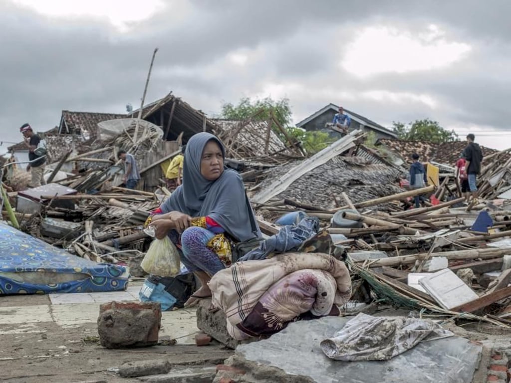 Eine Überlebende des Tsunamis in Sumur sitzt auf einem Haufen Schutt. Foto: Fauzy Chaniago/AP