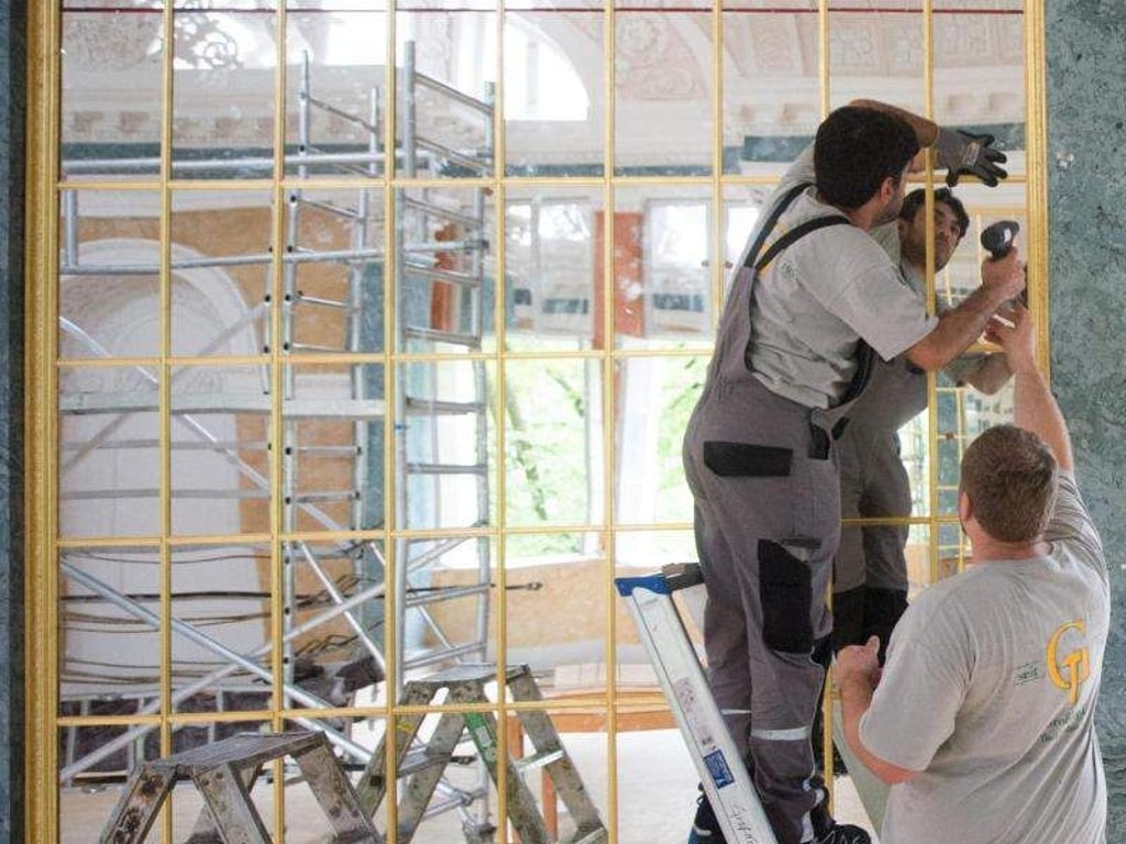 Ein Tischler setzt im Spiegelsaal des Schlosses eine vergoldete Holzleiste an einer Spiegelfläche ein. Foto: Klaus-Dietmar Gabbert/dpa-Zentralbild/ZB/Archiv