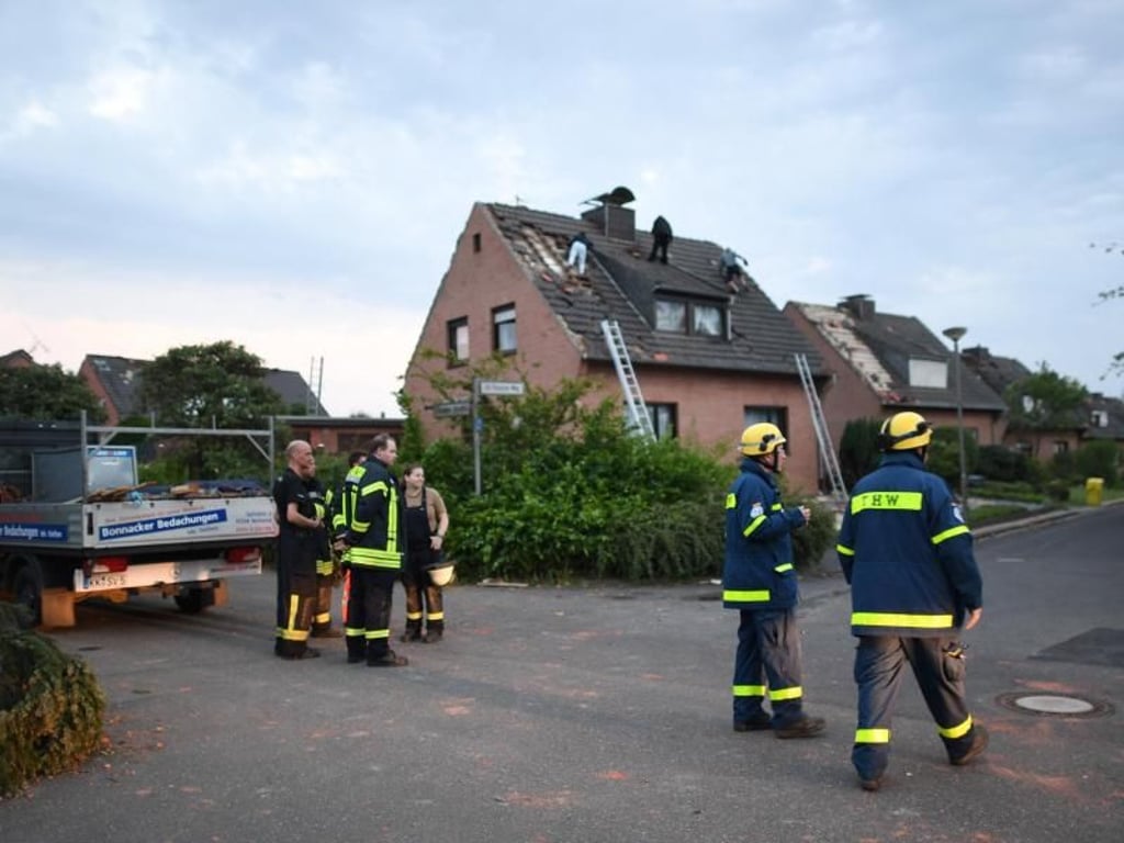 Einsatzkräfte der Feuerwehr und des THW stehen neben Häusern, die von einem Wirbelsturm beschädigt wurden. Foto: Federico Gambarini