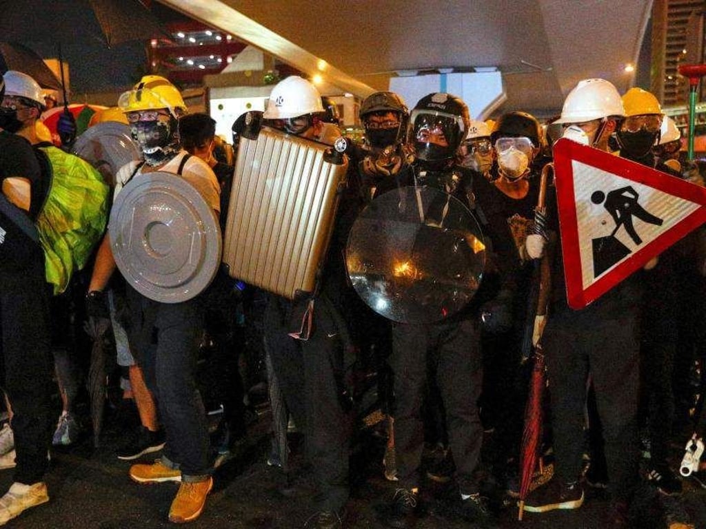 Demonstranten haben sich mit Straßenschildern, Koffern und Mülleimerdeckeln gegen die Schlagstöcke der Polizisten gewappnet. Foto: Bobby Yip/AP