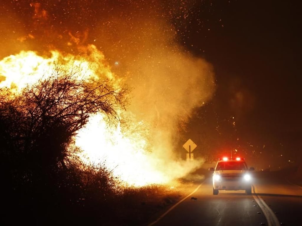 Unmittelbar neben brennendem Buschwerk rast ein Wagen der Feuerwehr unweit von San Diego zu seinem Einsatzort. Foto: K.C. Alfred/San Diego Union-Tribune