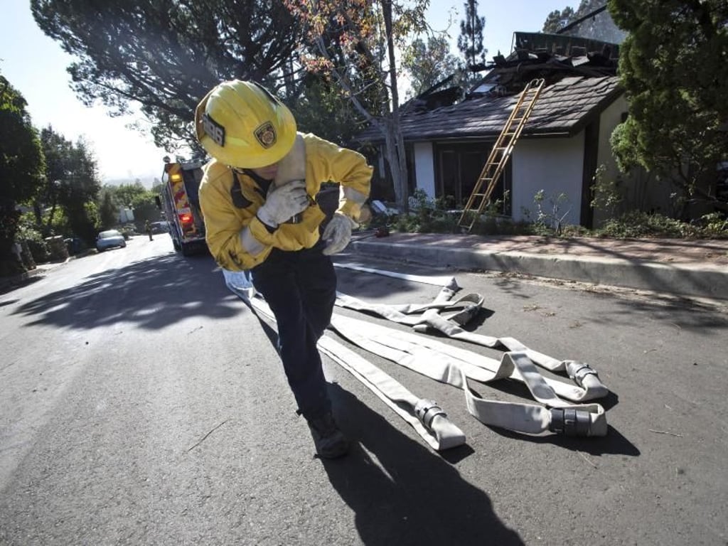 Ein Feuerwehrmann rollt in Bel Air Schläuche aus. Foto: Ed Crisostomo