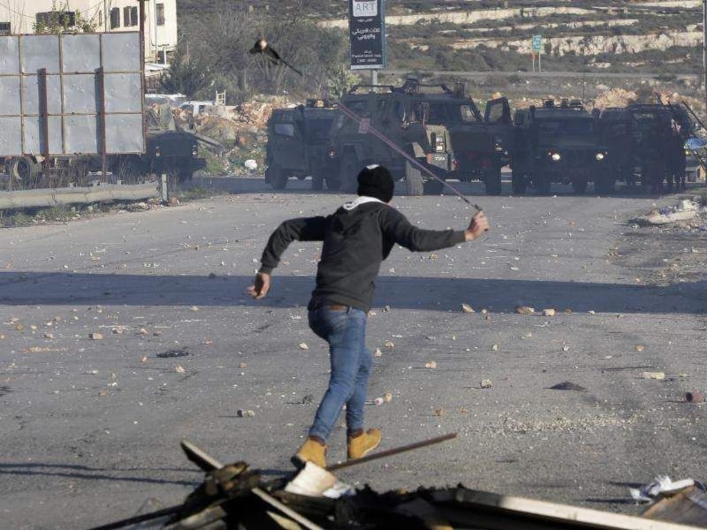 Ein Palästinenser wirft Steine auf israelische Sicherheitskräfte. Die israelische Armee hat die Stadt Ramallah, das Verwaltungszentrum der Palästinenser im Westjordanland, abgeriegelt. Foto: Mahmoud Illean/AP