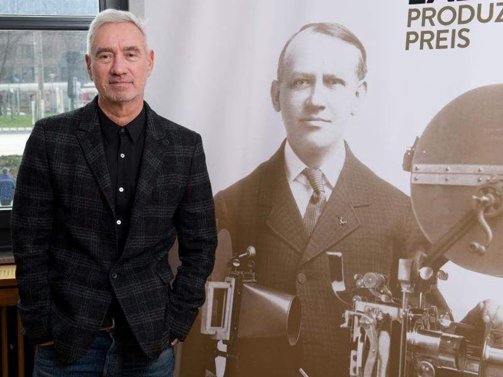 Der Regisseur Roland Emmerich neben einem Plakat, das den Filmpionier Carl Laemmle zeigt. Foto: Bernd Weissbrod