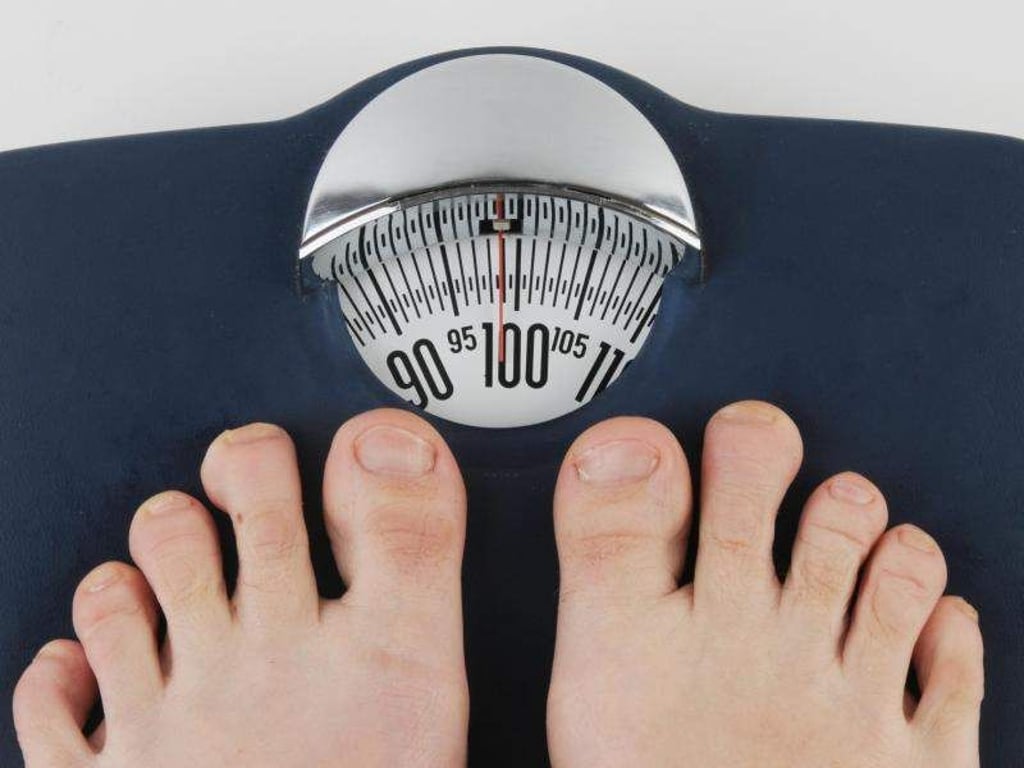 Männerfüße stehen auf einer Personenwaage. Foto: Armin Weigel/Archiv