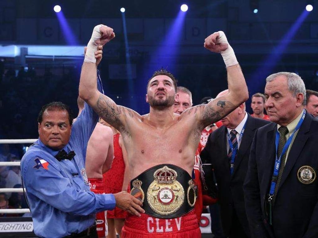 Nathan Cleverly (M) feiert seinen Sieg mit dem Gürtel des Halbschwergewichts-Champions. Foto: Ronny Hartmann