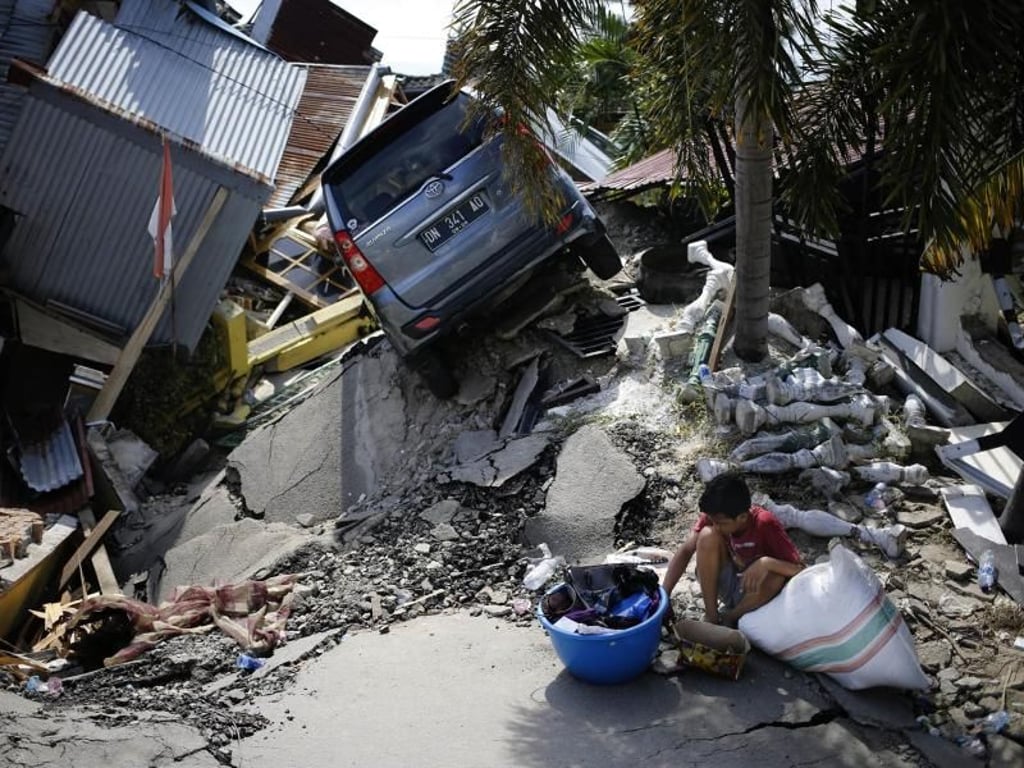 Ein Junge vor dem schwer beschädigten Haus eines Familienmitglieds. Foto: Dita Alangkara/AP