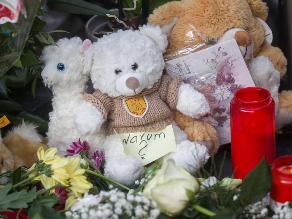 Ein Zettel mit der Aufschrift «Warum?» liegt neben Plüschtieren, Blumen und Kerzen. Foto: Frank Rumpenhorst