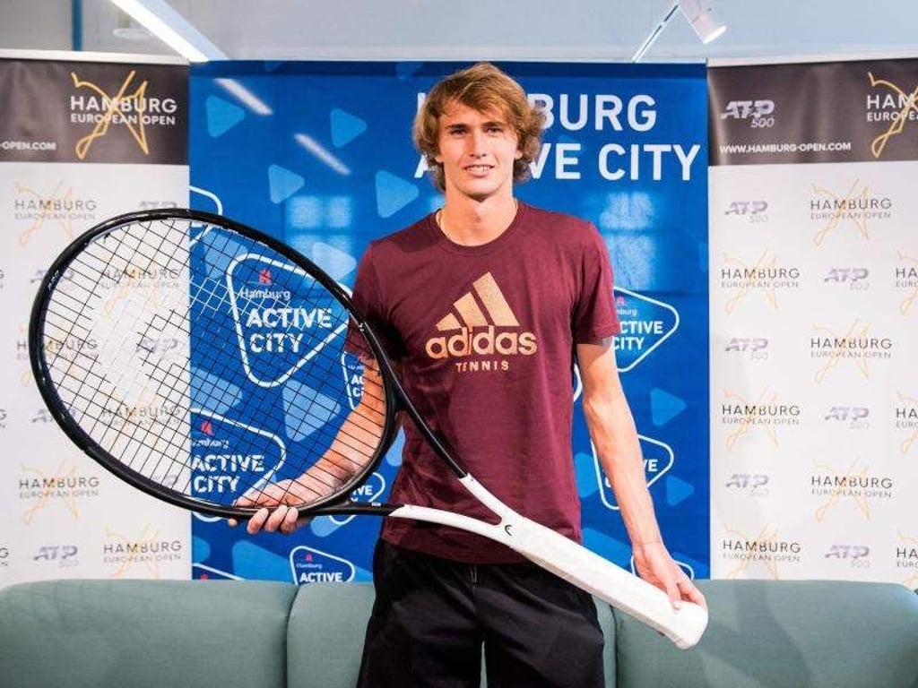 Alexander Zverev posiert in Hamburg während einer Pressekonferenz mit einem überdimensionalen Tennisschläger. Foto: Daniel Bockwoldt