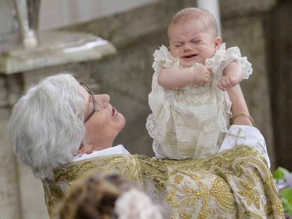 Der kleine Prinz sieht nicht sonderlich begeistert aus, als die Erzbischöfin der Schwedischen Kirche, Antje Jackelén, ihn über dem Taufbecken hochhebt. Foto: Jonas Ekstromer