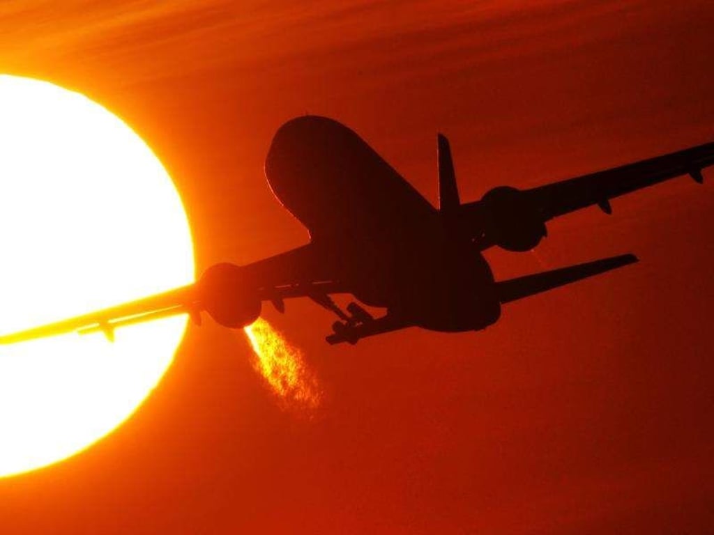 Ein Flugzeug startet vor der untergehenden Sonne. Foto: Julian Stratenschulte