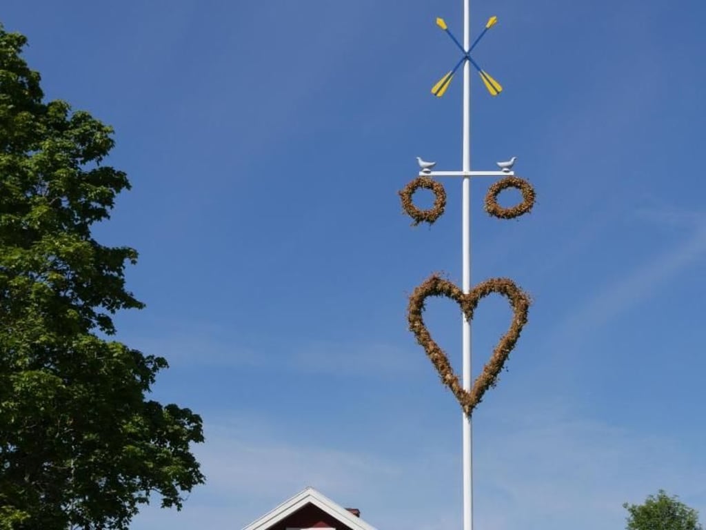 Jeder Ort schmückt seinen Midsommarbaum nach eigenen Traditionen und mit eigenen Symbolen - bei dieser Stange vor einer Festhalle in Rättvik sieht man etwa ein Herz, Ringe sowie Tauben. Foto: Isabelle Modler