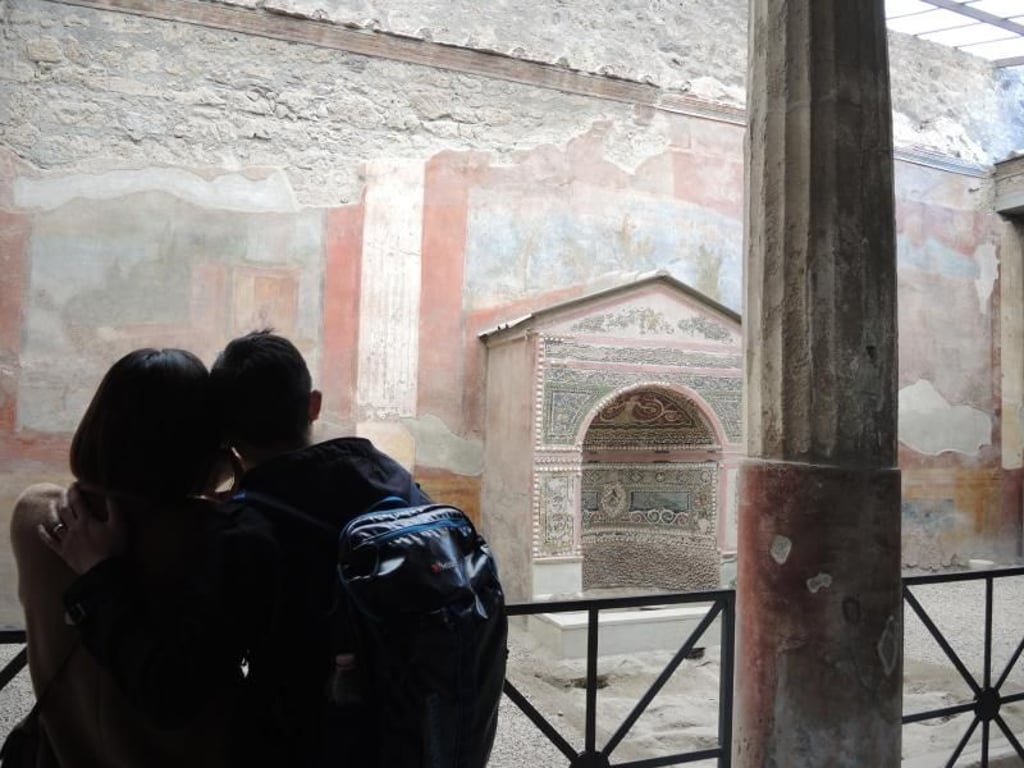 Ein junges Paar betrachtet einen Brunnen im Archäologischen Park Pompeji. Foto: Lena Klimkeit