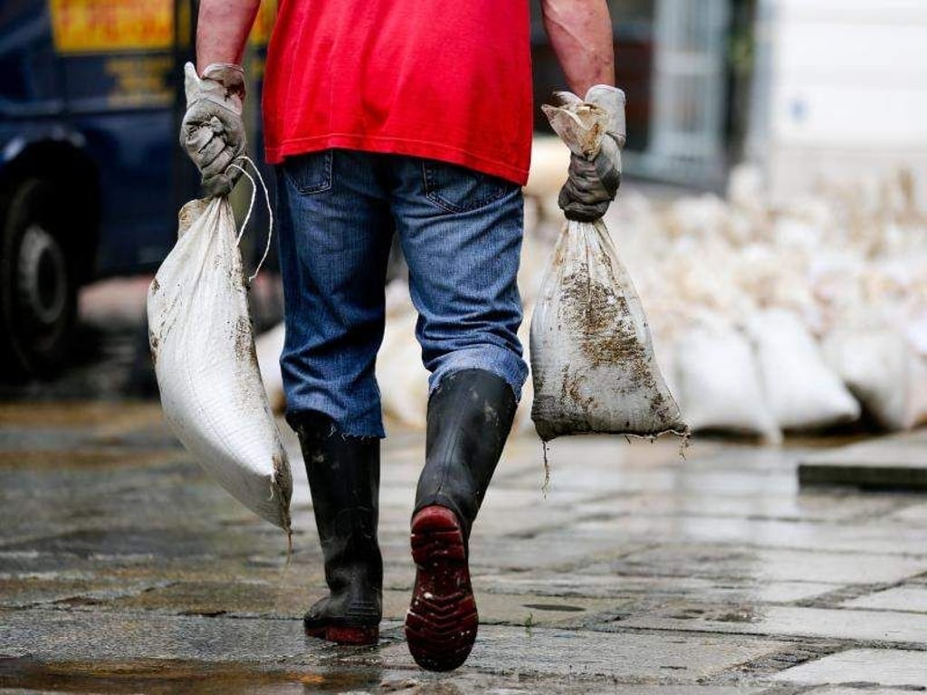 Ein Helfer räumt in der vom Elbehochwasser betroffenen Stadt Meißen (Sachsen) Sandsäcke von einer Straßen. Foto: Kay Nietfeld/Archiv