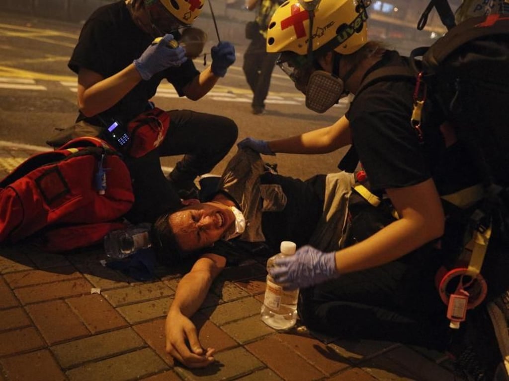 Sanitäter helfen einem von Tränengas getroffenen Demonstranten. Foto: Bobby Yip/AP