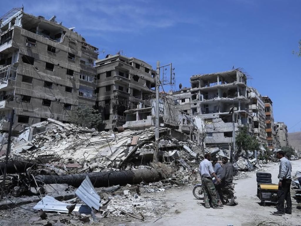 Menschen stehen vor zerstörten Gebäuden in Duma. Hier soll ein mutmaßlicher Chemiewaffenanschlag passiert sein. Foto: Hassan Ammar/AP