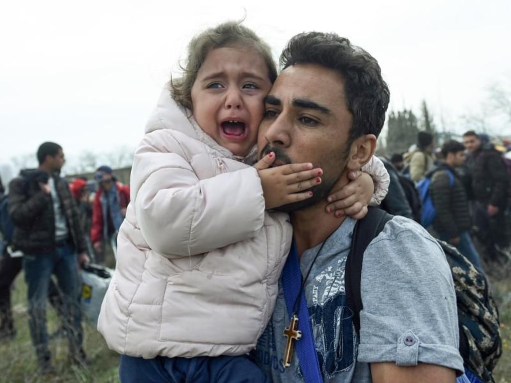 Ein Mann hält ein weinendes Mädchen. Die Hoffnung zahlreicher Migranten nach Mitteleuropa zu gelangen, schwindet nicht. Foto: Giannis Papanikos/AP