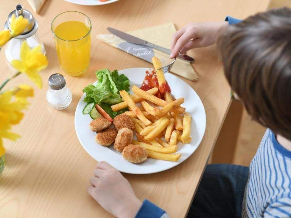 Ein Junge sitzt vor einem Teller mit Chicken Nuggets und Pommes Frites (Archiv). Foto: Tobias Hase