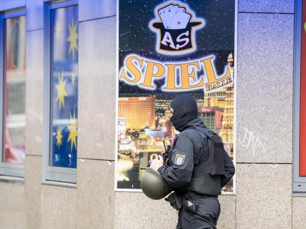 Ein vermummter Polizist geht im Frankfurter Bahnhofsviertel an einer Spielhalle vorbei, die Ziel einer Razzia ist. Foto: Fabian Sommer