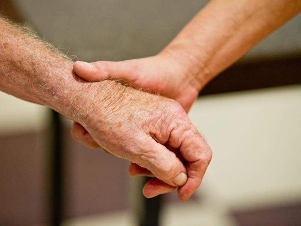 Eine auf Demenzkranke spezialisierte Altenpflegerin hält die Hand eines demenzkranken Mannes. Foto: Daniel Karmann/Symbolbild