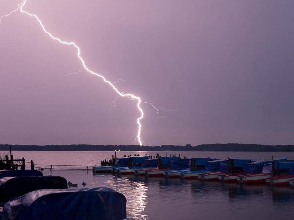 Ein Blitz entlädt sich in der Nacht hinter dem Tretbootsteg am Zwischenahner Meer in Niedersachsen. Foto: Mohssen Assanimoghaddam