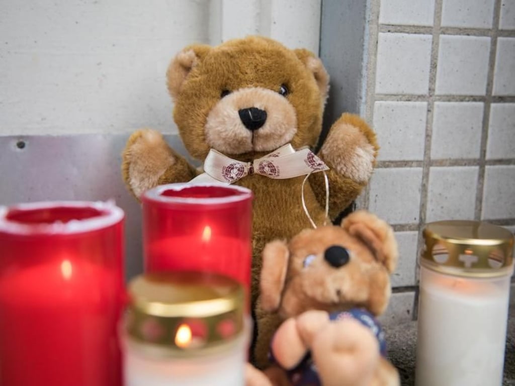 Kerzen und Teddybären aus Stoff stehen in Hamburg-Neuwiedenthal vor dem Mehrfamilienhaus. Foto: Daniel Bockwoldt