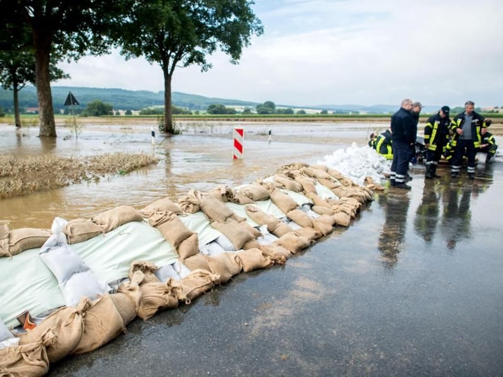 Hält der Damm? Feuerwehrleute wachen in Heersum über die aus Sandsäcken gebaute Wassersperre an einer überfluteten Straße. Foto: Hauke-Christian Dittrich