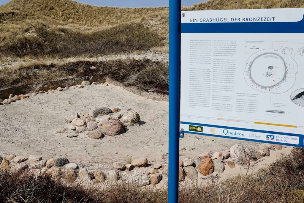 Ein Grabhügel aus der Bronzezeit ist als Denkmal in den Dünen am Strand zu sehen.