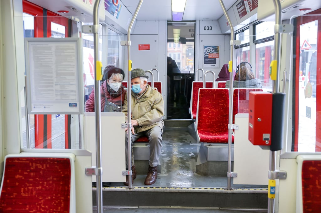 Ein älteres Ehepaar fährt in Halle mit Mund-Nasen-Schutz Straßenbahn.