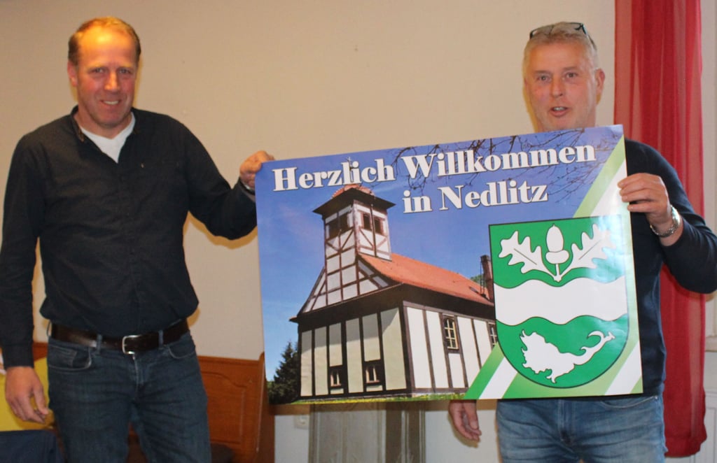 Ortsbürgermeister Mario Buge (r.) und sein Stellvertreter Jan de Vries präsentieren den Entwurf für ein Schild, das die Ortseingänge von Nedlitz bald zieren soll.
