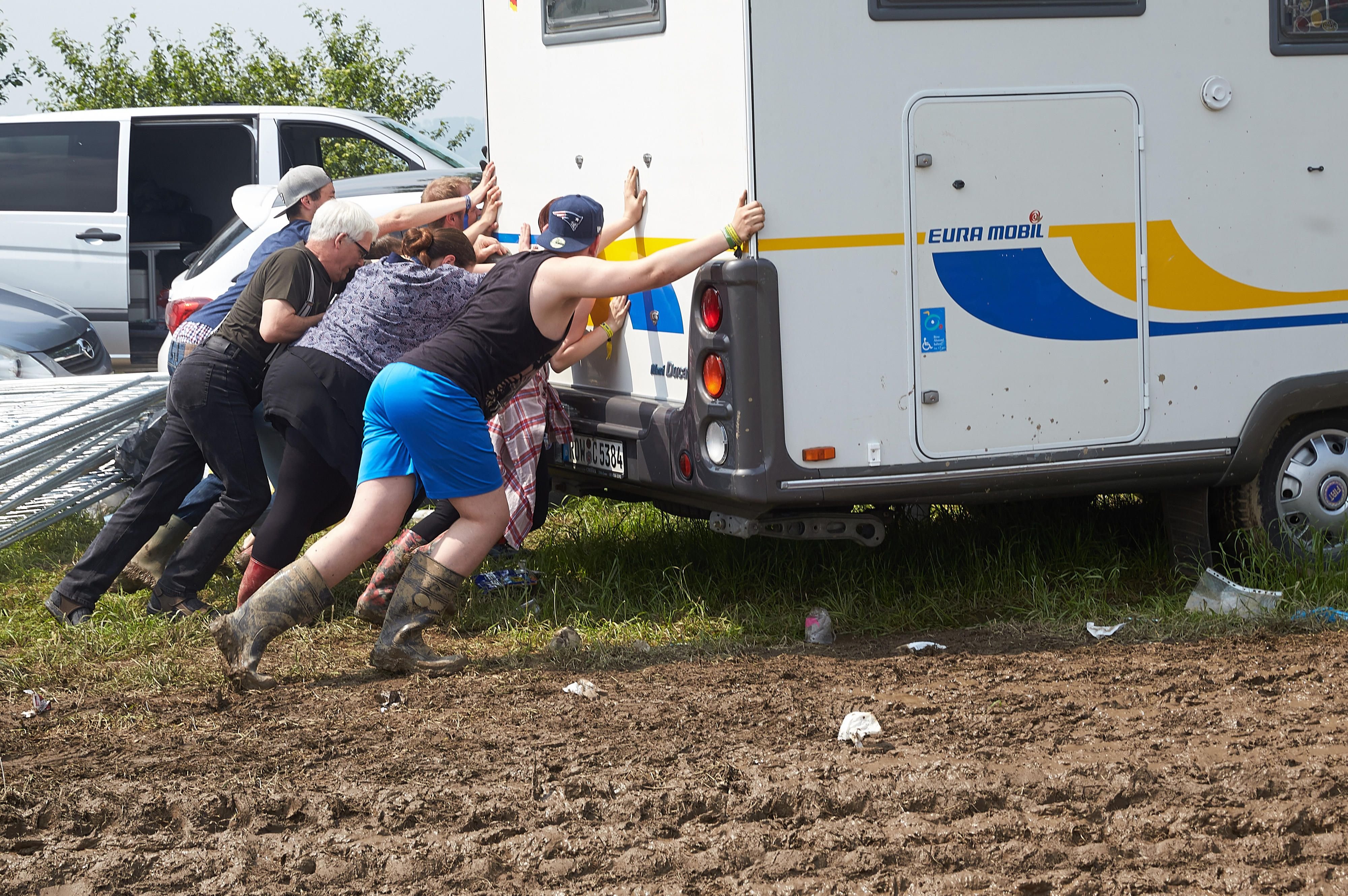 Festivalbesucher versuchen, ein Wohnmobil für die Rock-am-Ring-Abreise aus dem Schlamm zu schieben.