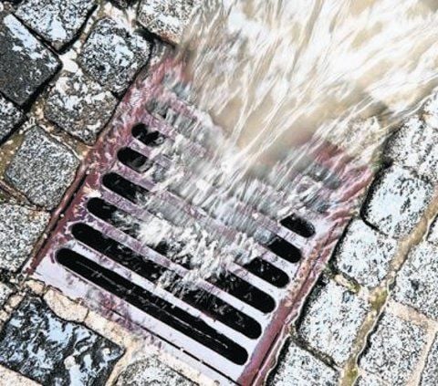 Regenwasser läuft in einen Kanal.