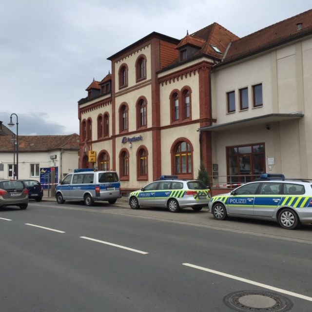 Streifenwagen der Polizei stehen nach dem Überfall vor der Postbank-Filiale in der Unteren Bahnhofstraße in Hettstedt.
