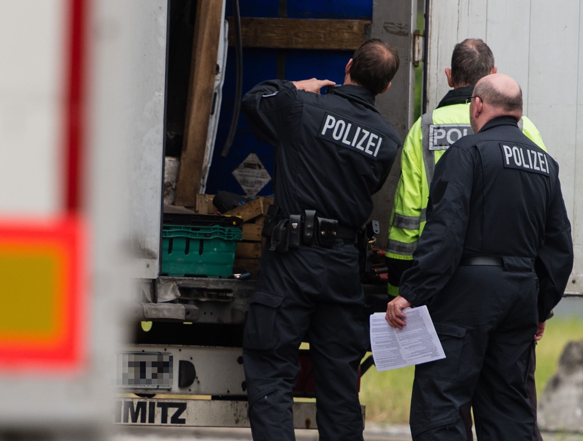 Polizisten untersuchen die Heckklappe eines Lkw.