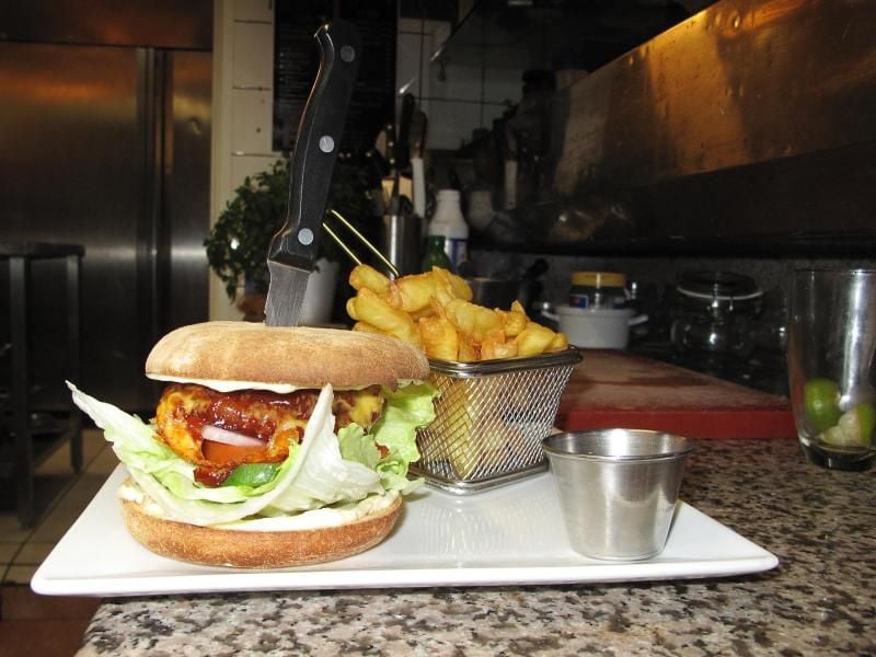 Restaurant-Inhaberin Edit Kiss mit Burger und Pommes. Foto: Simon Ribnitzky