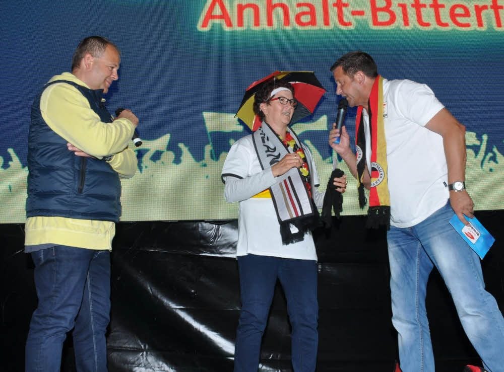 Frank Smirek von der Sparkasse (li.) und Moderator Steffen Häuseler überreichen Beate das Präsent.