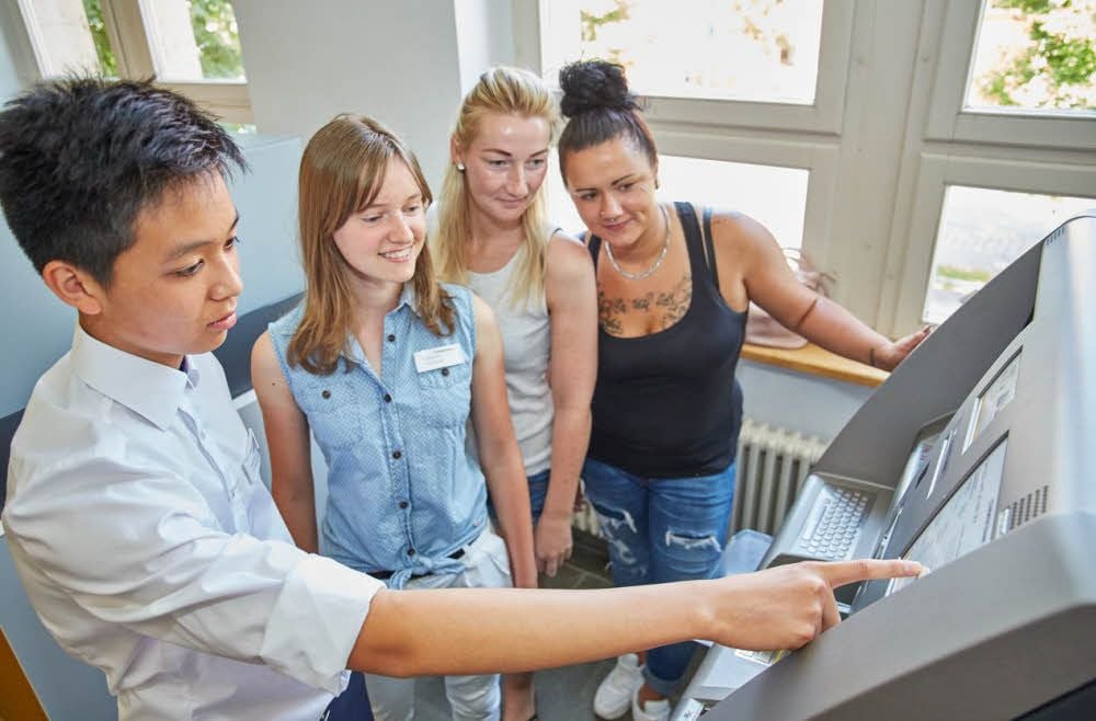 Tri Hoang Le und Julia Liebaug (Praktikanten) beraten Evelyn Günter und Vivien Bringezu am Geldautomaten in der Commerzbank (von links).
