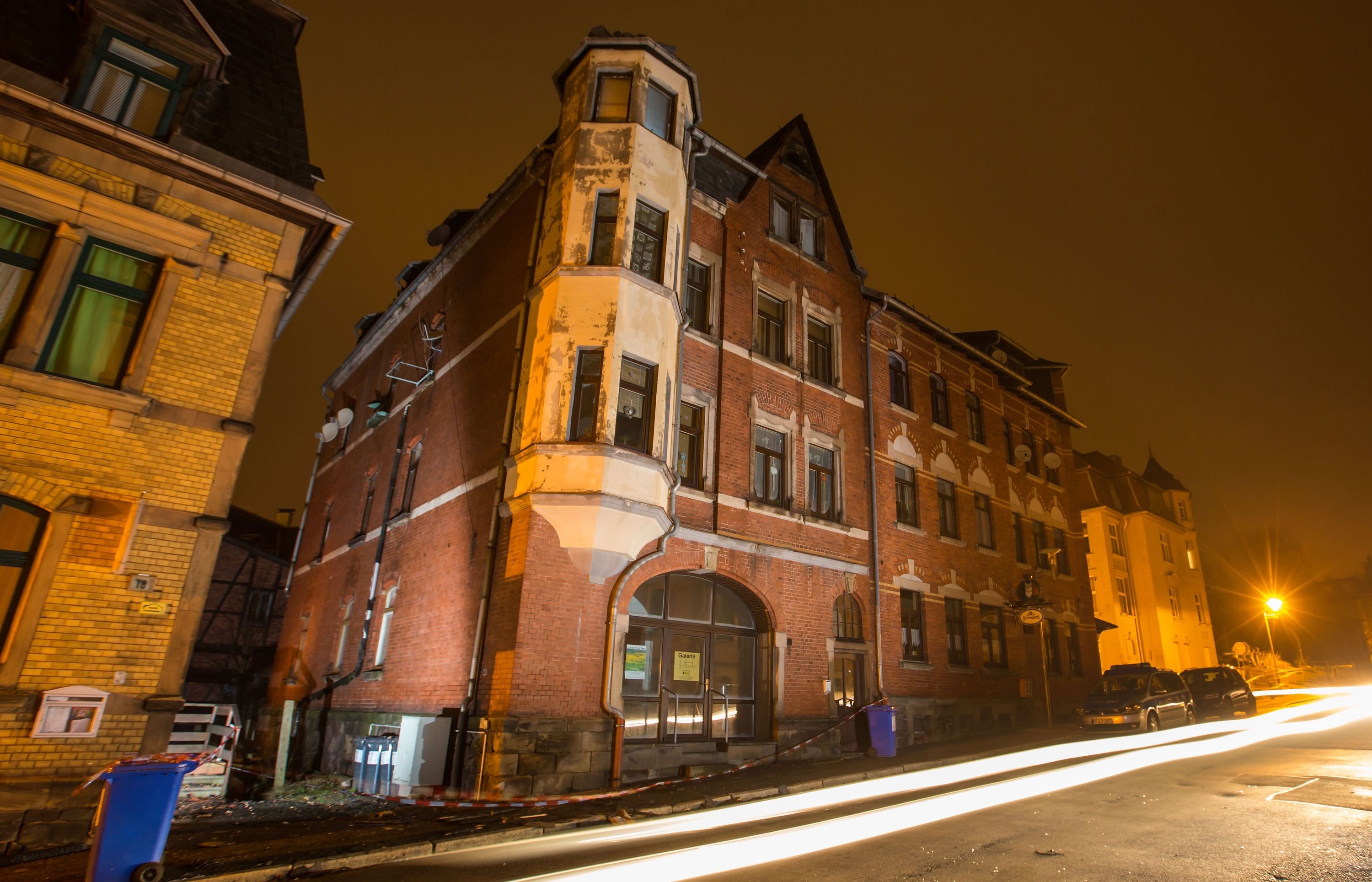 Ein Polizeiauto steht vor einem stark beschädigten Haus in Sonneberg
