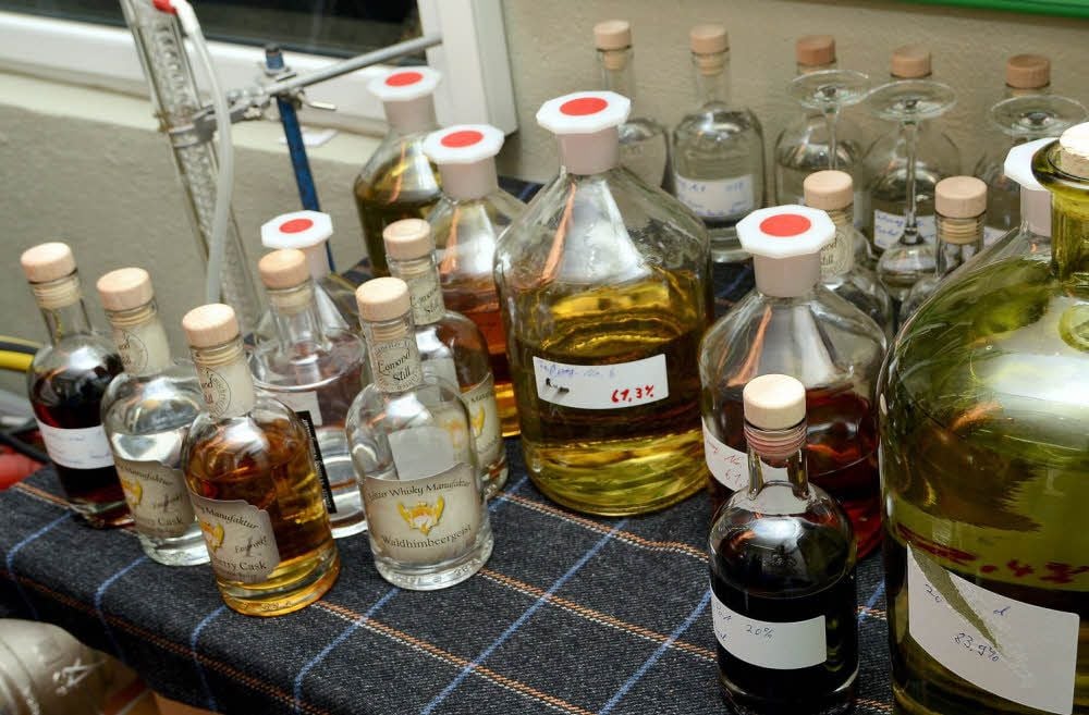 Die Arbeitsfläche in der Brennerei von Daniel Rost ist mit Flaschen vollgestellt, die Whisky unterschiedlicher Reifegrade enthalten.