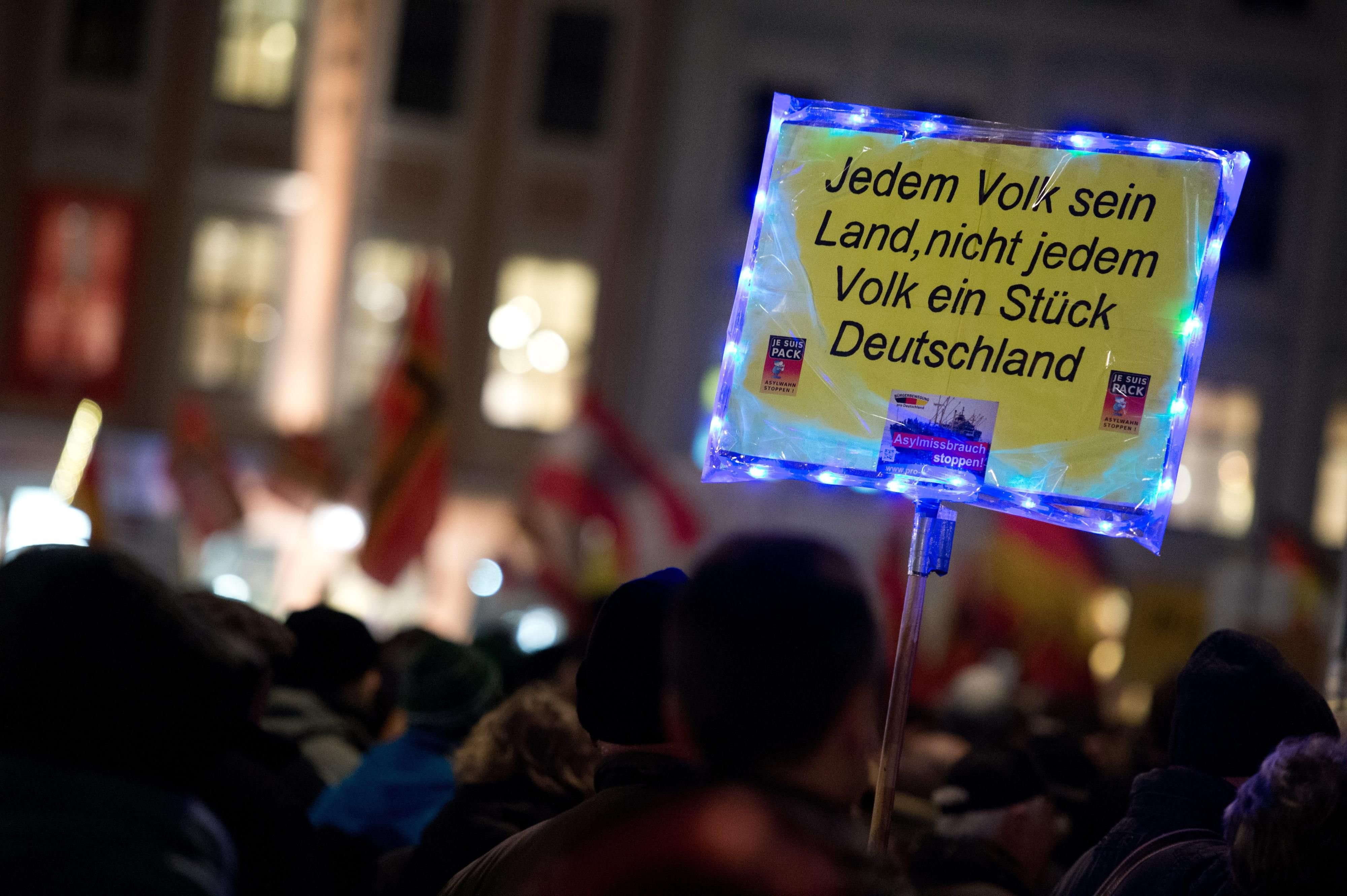 Anhänger der islamfeindlichen Pegida-Bewegung demonstrieren am 15.02.2016 mit einem Schild "Jedem Volk sein Land, nicht jedem Volk ein Stück Deutschland" vor der Frauenkirche in Dresden (Sachsen).