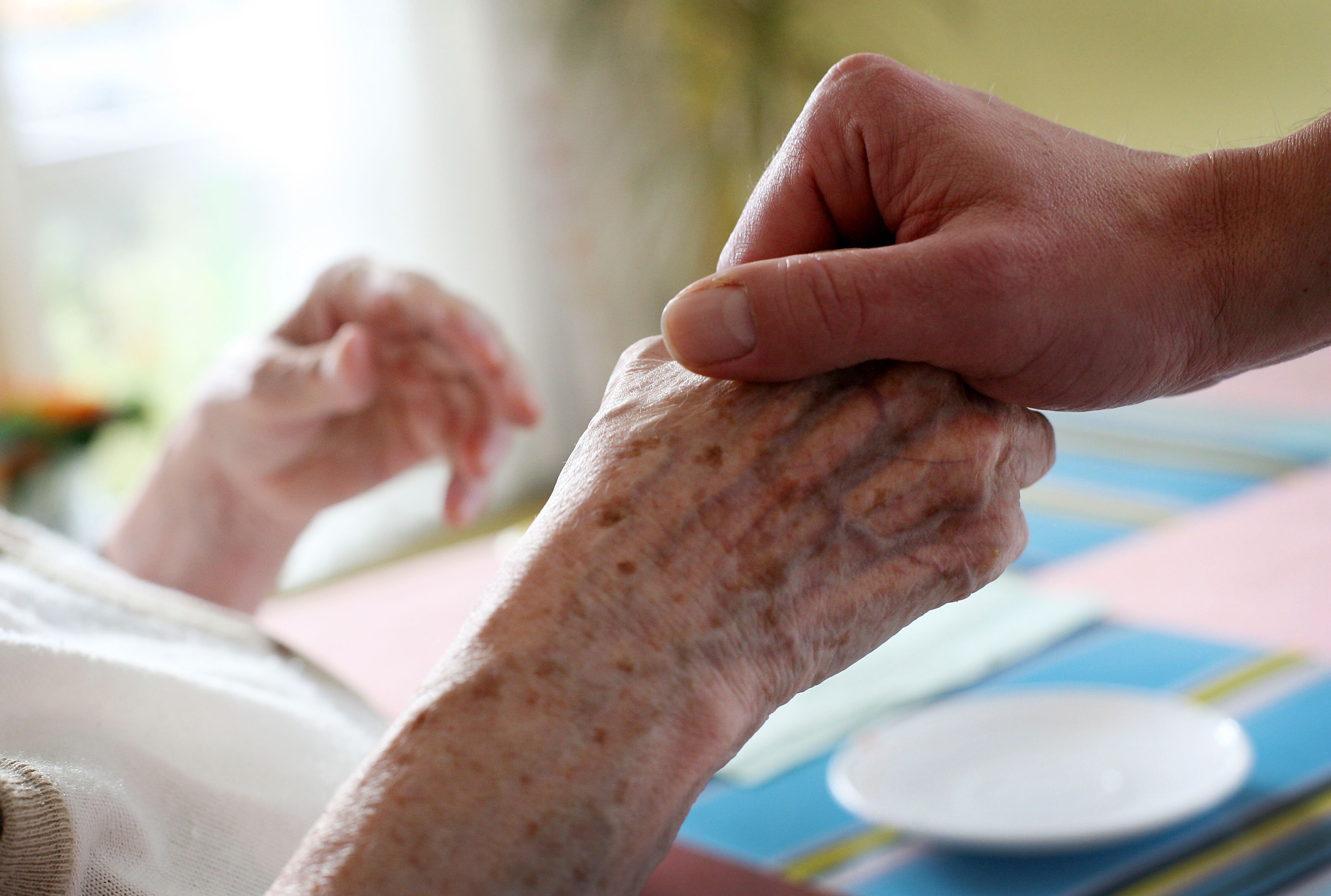 Ein Pfleger hält die Hand einer Patientin.