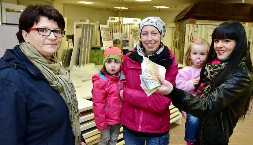 Rund 1.000 Euro hält Peggy Franzmann (mit Töchterchen Emilie auf dem Arm) in der Hand, dafür kann Andrea Bendrick (mit Tochter Mia) jetzt im Geschäft von Ulrike Meyhe (l.) Fliesen kaufen.