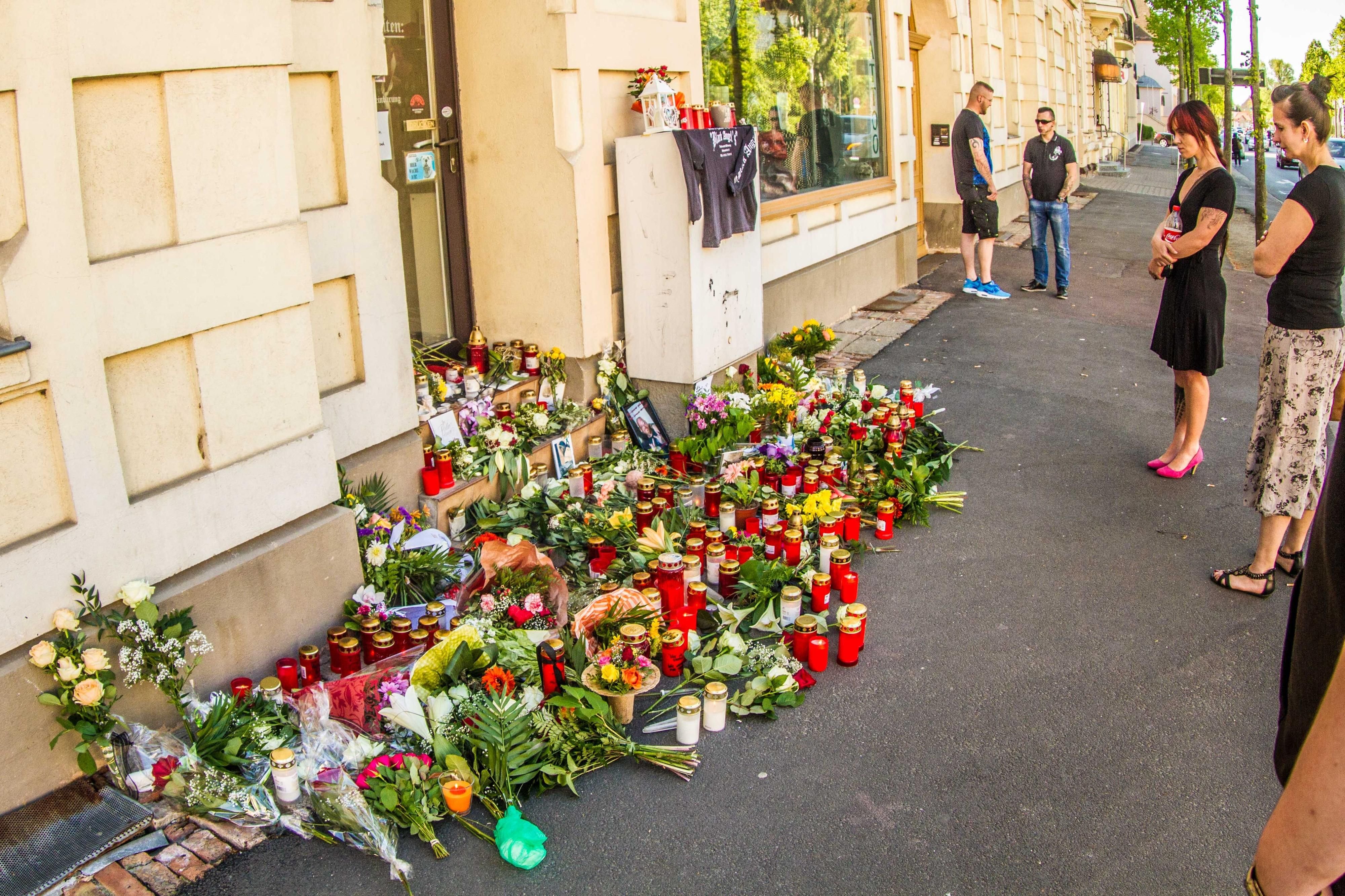 Blumen und Kerzen liegen vor dem Tattoostudio.