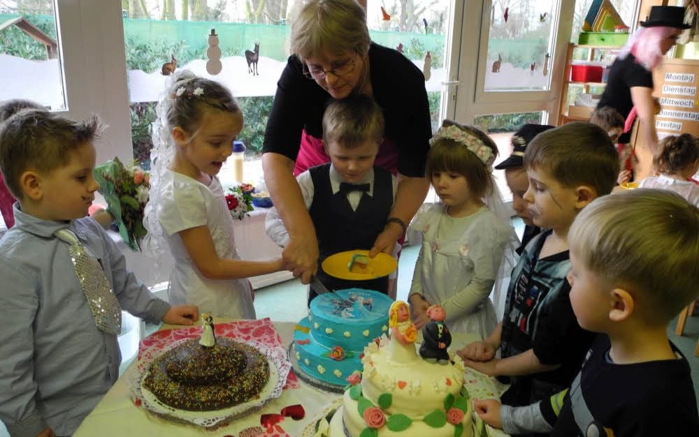 Gemeinsam mit Astrid Becker schneiden Kinder in der Tagesstätte „Koboldmühle“ die Hochzeitstorte(n) an.