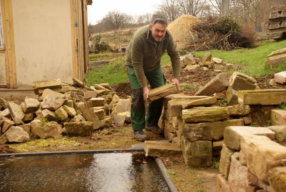 Andreas Ham legt eine alte Sandsteinmauer frei und richtet sie wieder her.