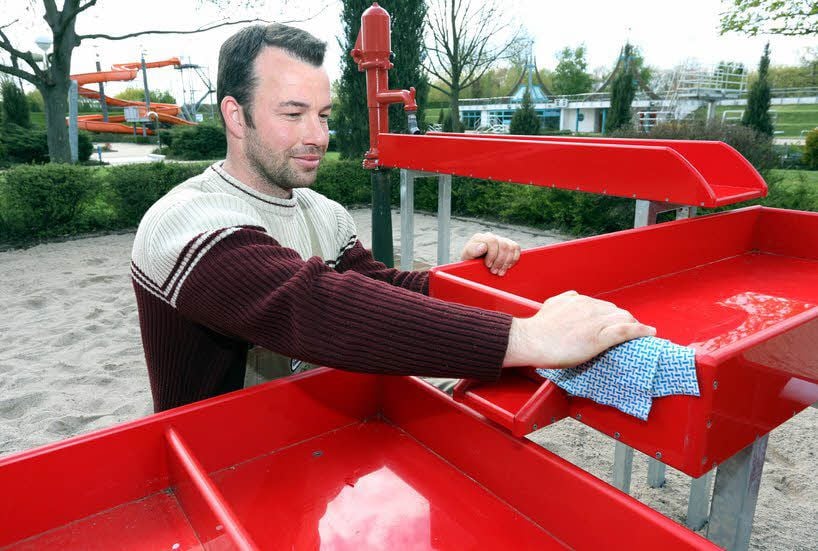 Schwimm-Meister Daniel Walther säubert die Spielgeräte auf dem Matschplatz.