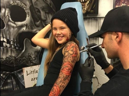 Dieses Mädchen hat Spaß beim vermeintlichen Tätowierer.