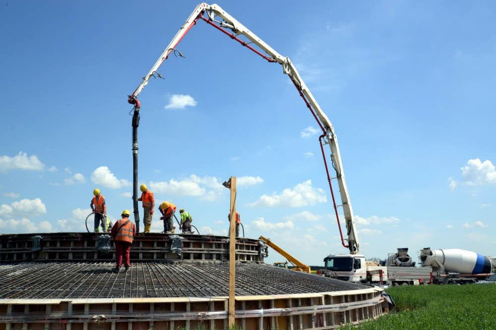 Lastwagen mit Mischtrommeln voller Fertigbeton rollen pausenlos an. Das Fundament muss in einem Stück gegossen werden.